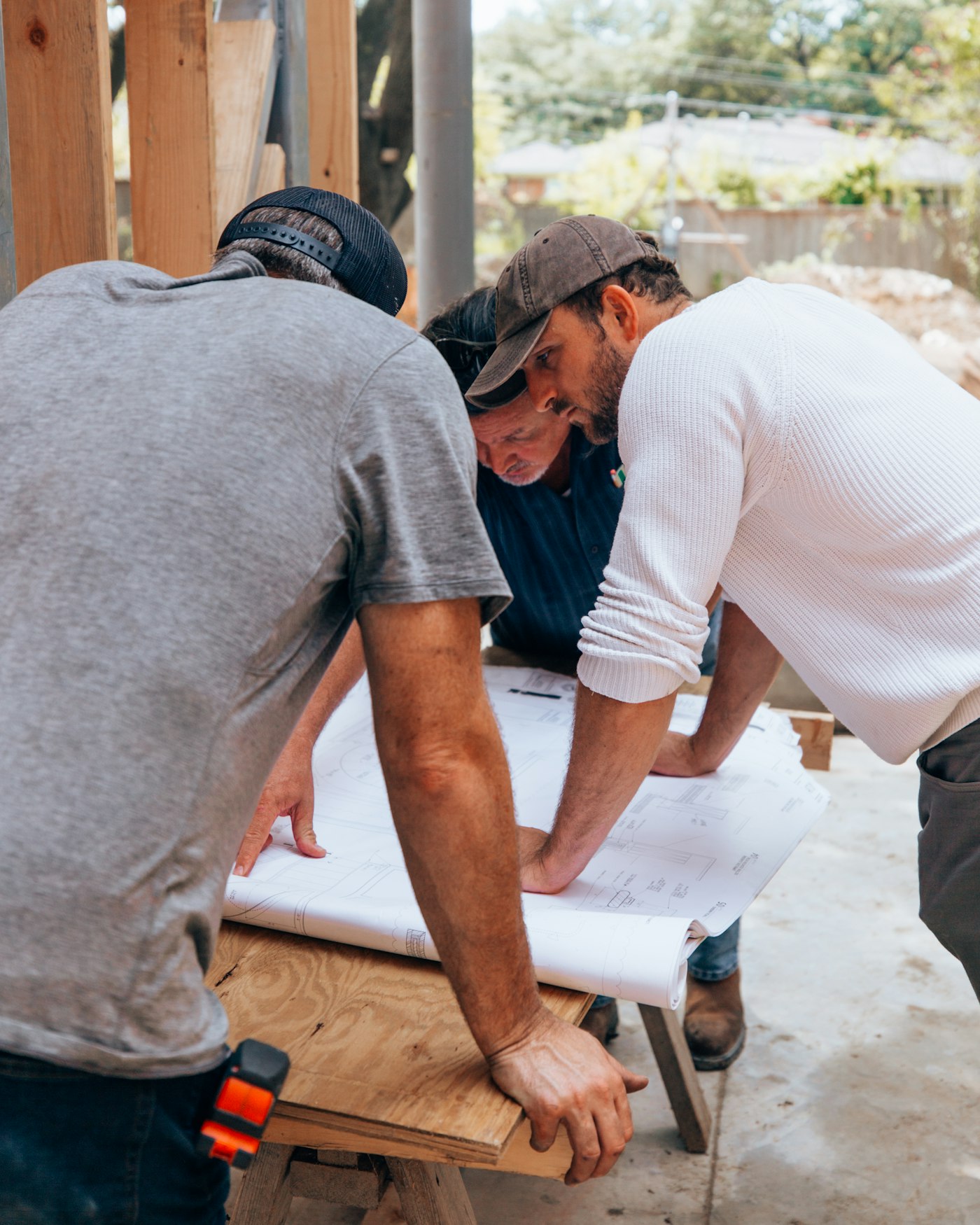 Two tradesmen reviewing a set of plans on a jobsite.